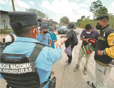  ?? YOSEPH AMAYA/REUTERS ?? revisa a documentos a hondureños que viajan en caravana a EU, en Corinto, Honduras