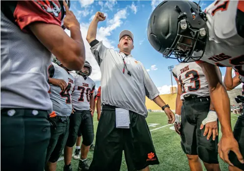  ?? PHOTOS BY JIM WEBER/THE NEW MEXICAN ?? Taos head coach Art Abreu Jr. pumps up his team before a scrimmage with West Las Vegas on Thursday at Ivan Head Stadium at Santa Fe High. The Tigers will play 2022 games on the road while their field is renovated. Abreu estimates the team will travel almost 2,000 miles this season.