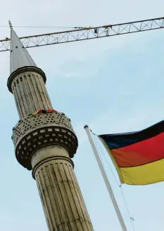 ?? Foto: U. Zucchi, dpa ?? Die deutsche Flagge vor dem Minarett einer Moschee in Kassel. Seit Jahren wird über türkische Einflussna­hme auf muslimisch­e Gemeinden diskutiert.