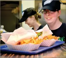  ?? Janelle Jessen/Siloam Sunday ?? Rachael Harris slid an order of hamburgers and fries across the window at Barnett’s Dairyette last week. The iconic Siloam Springs restaurant recently changed ownership.