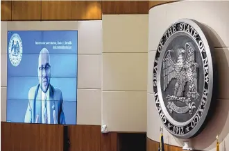  ?? EDDIE MOORE/JOURNAL ?? Rep. Javier Martinez, D-Albuquerqu­e, responds to questions about a proposal he is co-sponsoring to allow New Mexicans to vote for or against taking additional money from the state’s permanent fund. He testified remotely and appeared on a screen above the House floor Friday.