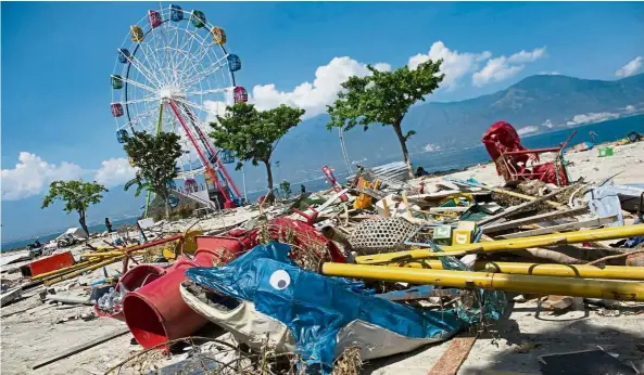  ??  ?? Colours of ruin: A ferris wheel standing amid debris at an amusement park in northern Palu. — AFP
