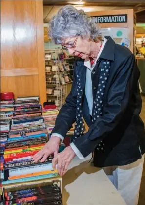  ?? WILLIAM HARVEY/RIVER VALLEY & OZARK EDITION ?? Carol Powers looks through books on a table in the Faulkner County Library, 1900 Tyler St. in Conway, where the semiannual Friends of the Faulkner County Libraries book sale will take place Friday and Saturday.