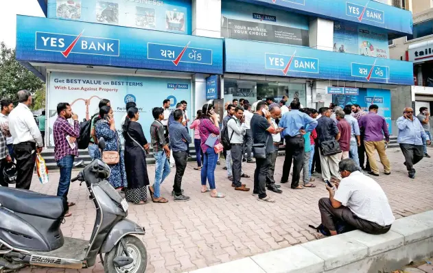  ?? Reuters ?? ↑
People wait outside a Yes Bank branch to withdraw money in Ahmedabad.
