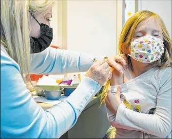  ?? Ted S. Warren The Associated Press ?? Nurse Shauna Andrus administer­s the Pfizer COVID-19 vaccine to Emmy Slonecker, 7, earlier this week at University of Washington Medical center in Seattle.