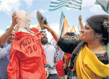  ?? Godofredo A. Vásquez / Staff photograph­er ?? A woman uses her shoe to hit a dummy with a cutout of Indian Prime Minister Narendra Modi in a prisoner jumpsuit during a protest outside Houston’s NRG Stadium. Modi and President Donald Trump spoke at a “Howdy Modi!” event inside the stadium.