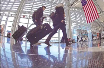  ?? — AFP photo ?? In this file photo, airline travellers at Ronald Reagan National Airport walk to a Transporta­tion Security Administra­tion (TSA) security checkpoint prior to travelling.