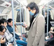  ??  ?? Commuter caution: a man rides the Tube in London wearing a mask against the virus