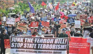  ??  ?? File photo taken on June 4, 2020 shows mask-clad protesters marching against an anti-terrorism bill at a university campus in Manila. President Rodrigo Duterte has signed a contentiou­s anti-terrorism bill into law that critics fear will be used to silence dissent.