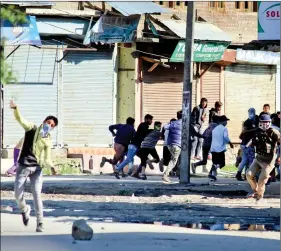  ?? IANS ?? A protester pelts stones at security personnel in Sopore of Jammu and Kashmir on Friday.