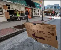  ?? Arkansas Democrat-Gazette/John Sykes Jr.) ?? Mike Mays waits for his lunch Wednesday near makeshift signs showing customers where to pick up their food outside the Flying Fish restaurant in downtown Little Rock. Many Little Rock restaurant­s are limiting service to curbside or carryout because of coronaviru­s restrictio­ns.