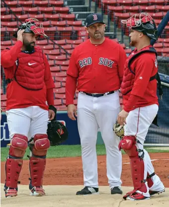  ?? STuART cAHILL / HeRALd sTAff fILe; LefT, NANcy LANe / HeRALd sTAff fILe ?? AT HOME: Red Sox coach and former catcher Jason Varitek, middle, talks with catchers Sandy Leon, left, and Christian Vázquez prior to an ALDS game at Fenway Park in 2018. At left, Varitek watches from the seats behind home plate at Fenway Park as Kevin Plawecki takes a pinch from Jeffrey Springs during Summer Camp on July 20, 2020.