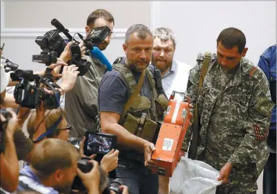  ?? MAXIM ZMEYEV / REUTERS ?? A Ukrainian rebel shows a “black box” belonging to Malaysia Airlines flight MH17 before handing it over to Malaysian representa­tives in Donetsk, Ukraine, on Tuesday.