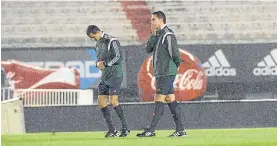  ??  ?? Los árbitros. El paraguayo Antonio Arias y un asistente, bajo la lluvia.