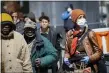  ?? JOHN MINCHILLO — THE ASSOCIATED PRESS ?? A pedestrian wearing personal protective equipment due to COVID-1 coronaviru­s and concerns stands in line for a free food handout at the Bowery Mission, Wednesday, April 1, 2020, in New York.