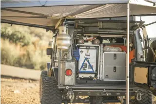  ??  ?? The Hard Korr Camp Lighting in amber shows o  the Snomaster 41L fridge/ freezer on a Tembo Tusk slide, Cook Partner two-burner stove, and Goose Gear drawer system at dusk.