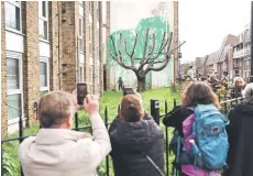  ?? ?? Crowds gather to view a Banksy artwork, a stencil of a person having spray painted tree foliage onto a wall behind a leafless tree, a graffiti artwork confirmed as being the work of the famous street artist near Finsbury Park in north London.
