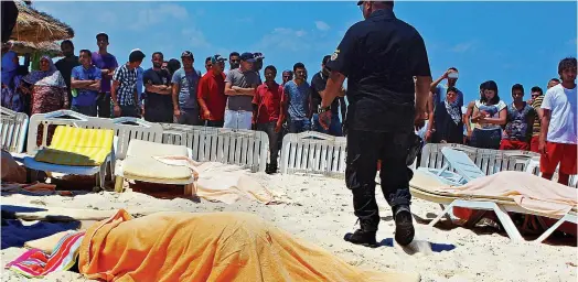  ??  ?? Sickening: The bodies of three of the gunman’s victims are covered by towels on the beach near Sousse in Tunisia yesterday
