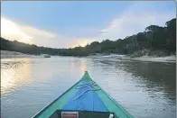  ?? PETER PRENGAMAN / AP ?? Left: A sunset in the Amazon rain forest is seen from a tributary of the Rio Negro outside Manaus, Brazil. Right: Young tourists look on as a man feeds fish to pink dolphins in the Rio Negro.