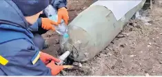  ?? ?? One of the Ukrainian troops pours water on the bomb while the other defuses it by hand