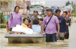  ??  ?? Members of a rescue team help a family evacuate a flooded zone in the southern Thai village of Chauat yesterday.—AFP