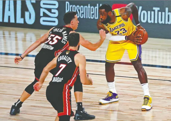  ?? PHOTOS: KIM KLEMENT/ USA TODAY SPORTS ?? The L.A. Lakers' LeBron James is defended by Miami's Duncan Robinson in Game 1 of the NBA Finals on Wednesday at AdventHeal­th Arena.