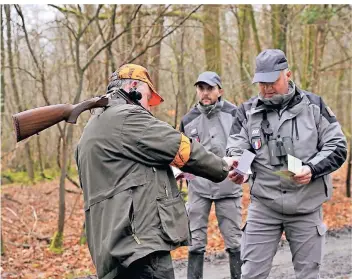  ?? FOTO: ALAIN DE BOT/DPA ?? Zwei Beamte der Umweltpoli­zei kontrollie­ren den Jagdschein eines Hobby-Waidmanns.