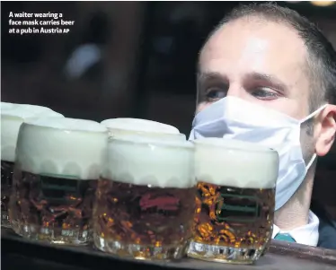  ?? AP ?? A waiter wearing a face mask carries beer at a pub in Austria