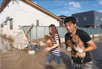  ?? AFP / Getty Images ?? Residents rescue dogs from a flooded area in Kurashiki, in western Japan. More than 3 million people have been told to evacuate to safer locations such as school buildings or city shelters.