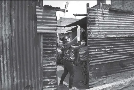  ?? AFP ?? A woman hangs a white flag at her door as a signal she needs to be delivered food at La Brigada neighborho­od in Guatemala City during the coronaviru­s pandemic. Hanging white or red flags on the facade of their homes as a request for help for food and medicine is the final hope to which Guatemalan­s cling in difficult times without income from the quarantine implemente­d on March 15 by the authoritie­s.