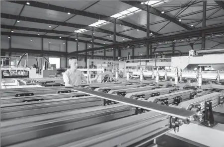  ?? PHOTOS BY LU ZHIPENG / FOR CHINA DAILY ?? Above: A worker operates on a production line of export-bound tiles in Nanxun district of Huzhou, Zhejiang province, in August 2020. Below: Workers transport wooden tiles at the workshop of Treessun Flooring Co Ltd in Nanxun district of Huzhou in March 2020.