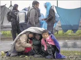  ?? DARKO BANDIC/ASSOCIATED PRESS ?? Children take shelter from the rain Monday in Sredisce ob Dravi, at the Croat-Slovenian border. Hundreds of migrants spent the night in rain and cold after being refused entry into Slovenia. Slovenia said some 5,000 people reached its borders Monday,...