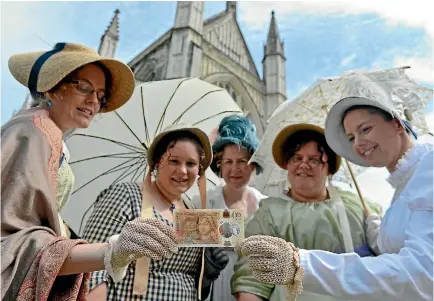  ?? PHOTO: GETTY IMAGES ?? Women in period costume pose with one of the Bank of England’s new 10-pound notes, featuring author Jane Austen, during its unveiling yesterday, the 200th anniversar­y of Austen’s death, at Winchester Cathedral, where she is buried.