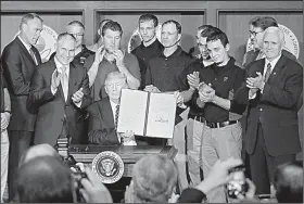  ?? AP/PABLO MARTINEZ MONSIVAIS ?? President Donald Trump, surrounded by coal miners, Interior Secretary Ryan Zinke, Environmen­tal Protection Agency Director Scott Pruitt, Energy Secretary Rick Perry and Vice President Mike Pence, shows the executive order he signed Tuesday at EPA...