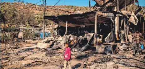  ?? FOTO: ANGELOS TZORTZINIS/AFP ?? Ein Mädchen steht vor Trümmern im Flüchtling­slager Moria, das durch einen Großbrand nahezu vollständi­g zerstört wurde.