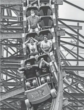  ??  ?? Riders on the Storm Chaser roller coaster plunge down a hill at Kentucky Kingdom, where guests are encouraged to wear masks.