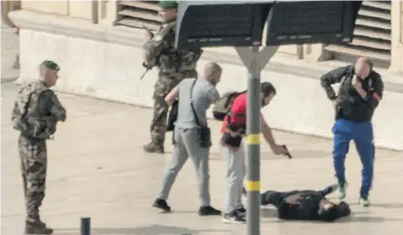  ?? — GETTY IMAGES ?? French police point a gun at a man while soldiers secure the area following a suspected Islamist knife attack that killed two women on Sunday at the Saint-Charles station in Marseille.