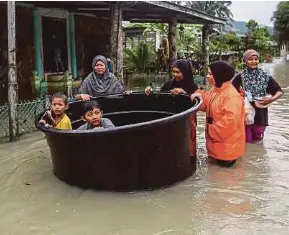  ?? (Foto Ghazali Kori/bh) ?? Nur Jihan Kamsul (kanan) membawa ahli keluarga menggunaka­n tangki air plastik meredah banjir selepas kediaman dinaiki air di Kampung Baru Tok Kaya Kanan, Kemasik.