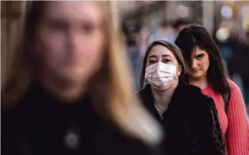  ?? JEENAH MOON TNS ?? A woman wearing a protective mask walks near the Columbia University campus on March 9 in New York City. The university is canceling classes for two days after a faculty member was quarantine­d for exposure to the novel coronaviru­s.