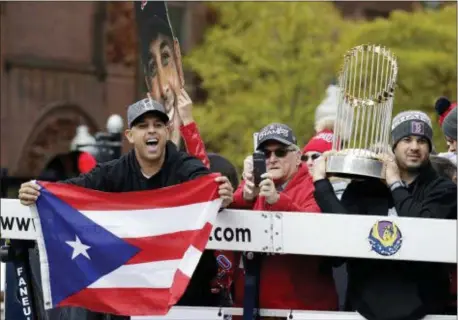 ?? ELISE AMENDOLA — THE ASSOCIATED PRESS ?? Red Sox manager Alex Cora, left, waves the flag of Puerto Rico as coach Ramon Vazquez holds the championsh­ip trophy during a parade to celebrate the team’s World Series championsh­ip on Wednesday in Boston.