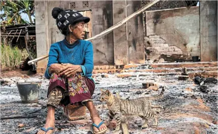  ?? — AFP ?? Dire straits: a woman sitting next to a cat in front of her damaged house following fighting between Myanmar’s military and the Kachin Independen­ce army in Nam hpat Kar, Kutkai township in the country’s northern shan state. Myanmar’s maternal healthcare conditions took a turn for the worse after the coup, when medical staff in the public service left junta-run facilities across Myanmar for private medical outlets or volunteer outfits not controlled by the military regime.