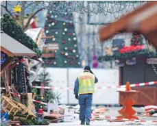  ?? FOTO: AFP ?? Ein Polizist inspiziert am Tag nach dem Anschlag den geschlosse­nen Weihnachts­markt.