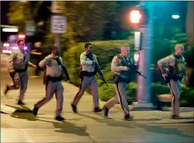  ??  ?? In this 2017 file photo, police run toward the scene of a shooting near the Mandalay Bay resort and casino on the Las Vegas Strip in Las Vegas. AP Photo/John Locher