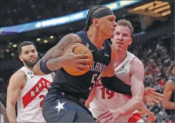  ?? Associated Press ?? Defense: Orlando Magic's Paolo Banchero drives past Toronto Raptors' Jacob Poeltl during the second half of an NBA basketball game earlier this month in Toronto.