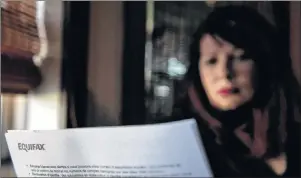  ?? CHRISTOPHE­R KATSAROV/THE CANADIAN PRESS ?? Robin Harvey poses in her Toronto home with a letter she received from Equifax advising her that her personal data had been compromise­d by a computer hack, on Thursday, Oct. 19.