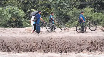  ??  ?? En San Pedro Sula las autoridade­s de Copeco han evacuado a varias personas por las crecidas de los ríos, ellos tratan de sacar sus pertenenci­as pese a la diecultad de transitar por las calles.