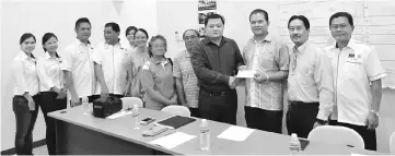  ??  ?? Huang (fourth right) presents a grant cheque to Sarikei Buddhist Orthodox Temple Committee representa­tive Chan Phan Chan.