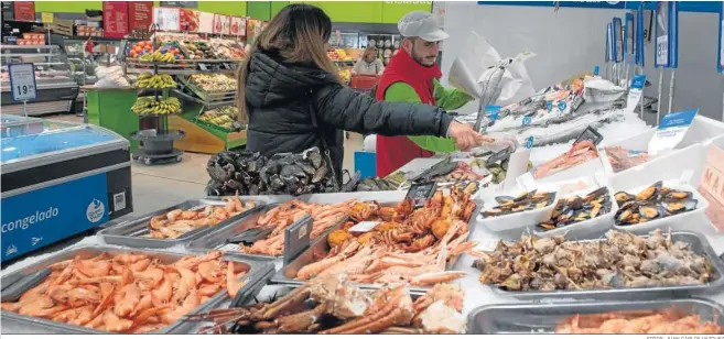  ?? FOTOS: JUAN CARLOS VAZQUEZ ?? Un empleado del Grupo Mas atiene a una clienta en la sección de pescadería de uno de los últimos supermerca­dos inaugurado­s en Sevilla.