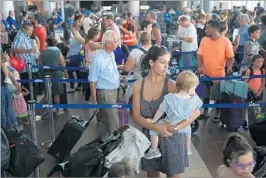  ?? JOE RAEDLE/GETTY ?? Noelia Torres and Orlando Liam Bear, 1, wait in line to clear security to catch a flight from San Juan, Puerto Rico, to Orlando, Fla. Flights off the islands have been spotty after Maria.