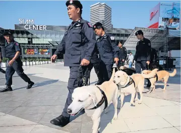  ??  ?? FOLLOWING THEIR NOSES: Bomb disposal experts patrol with sniffer dogs outside Siam Center, near the site of last week’s bombings.